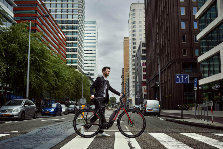 Mann schiebt ein E-Bike über einen Zebrastreifen