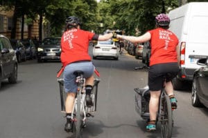 Zwei Fahrerinnen auf E-Cargobikes beim Faust-Gruß