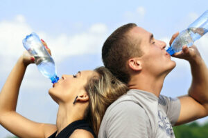 Eine Frau und ein Mann trinken jeweils eine Flasche Wasser